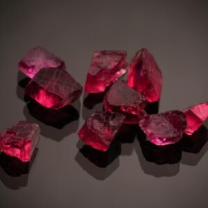Close-up photo of vibrant red gemstones on a shiny black surface, showcasing brilliance.